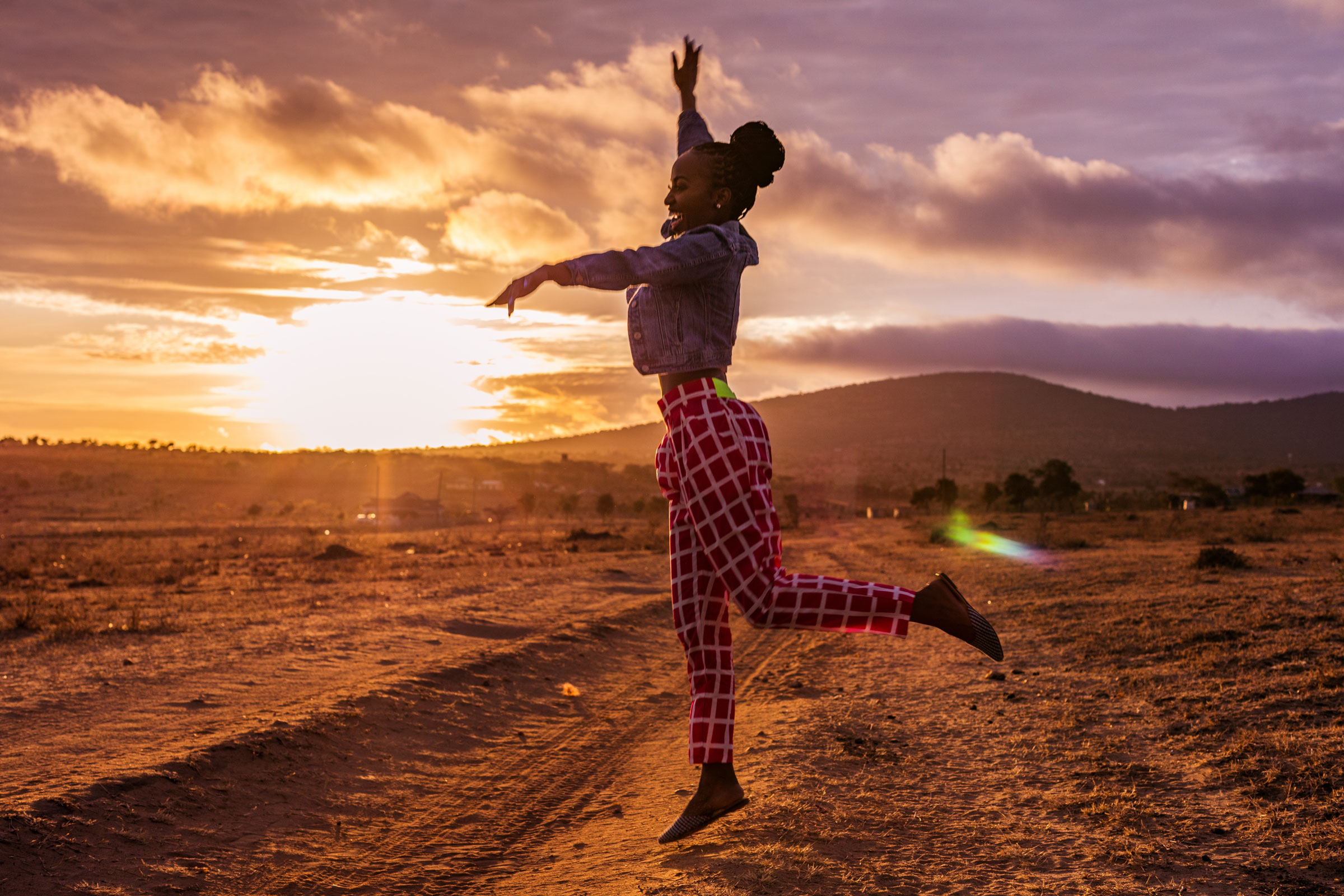 A woman leaping joyfully outdoors at golden hour, representing vitality and healthy aging.